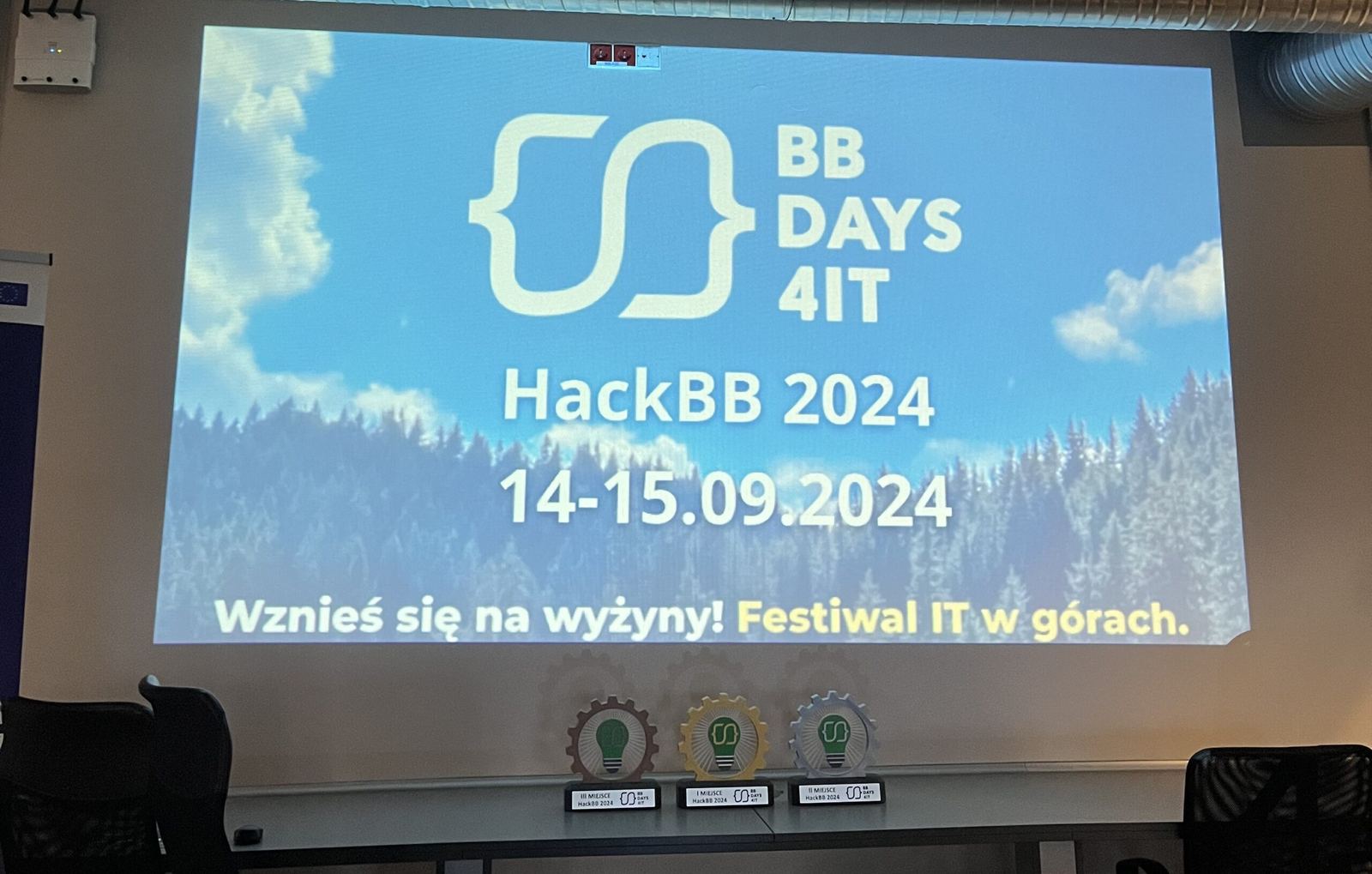 Ekran z logo HackBB 2024 i datą 14–15.09.2024 w sali hackathonu